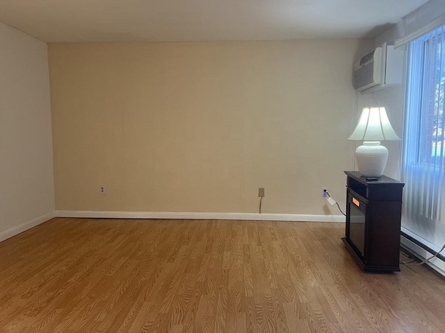 empty room with a wall mounted AC and light hardwood / wood-style flooring