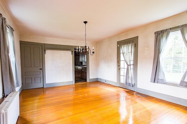 67 E Main St, West Brookfield, MA 01585 - unfurnished dining area featuring radiator, light wood-type flooring, a chandelier, and baseboards