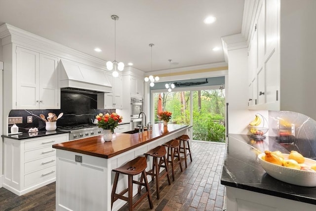 kitchen featuring a sink, butcher block countertops, decorative backsplash, white cabinets, and double oven