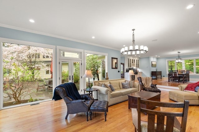 living area with a chandelier, crown molding, french doors, recessed lighting, and light wood-style flooring