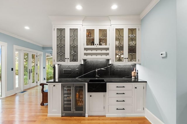 indoor bar with wine cooler, ornamental molding, backsplash, light wood-style flooring, and recessed lighting