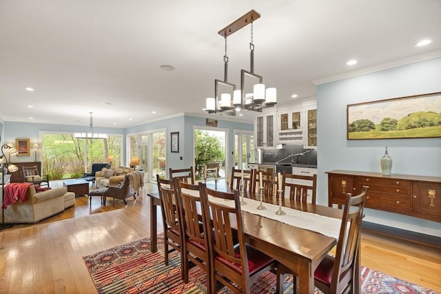 dining room featuring a chandelier, ornamental molding, wood finished floors, and recessed lighting