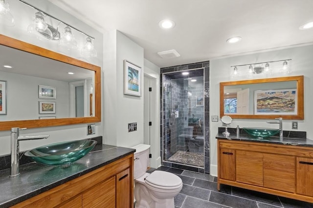 full bathroom with toilet, a stall shower, two vanities, and recessed lighting