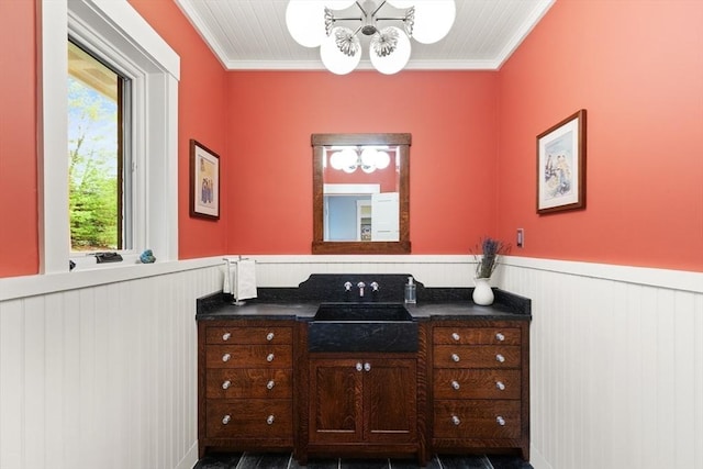 bathroom with a chandelier, wainscoting, crown molding, and vanity