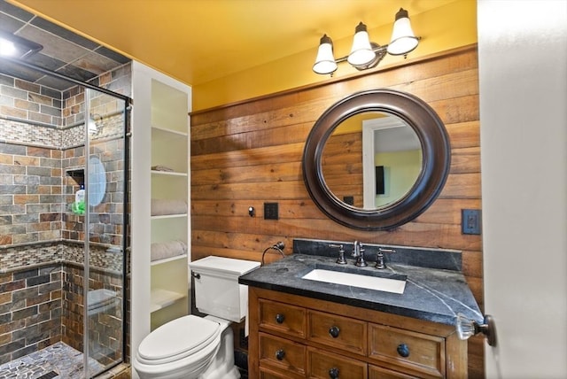 bathroom featuring wooden walls, a shower stall, vanity, and toilet