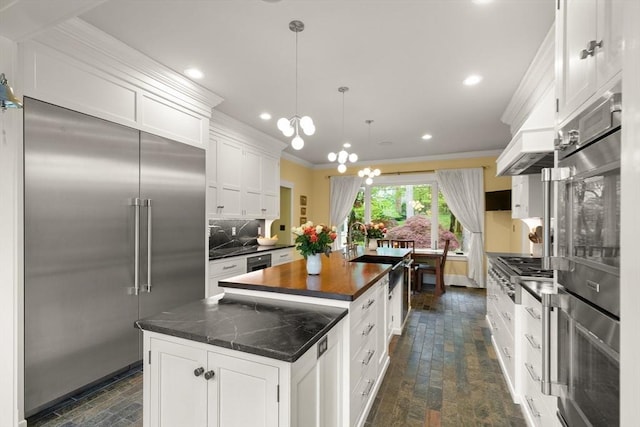kitchen featuring stainless steel appliances, a center island with sink, crown molding, white cabinets, and decorative backsplash
