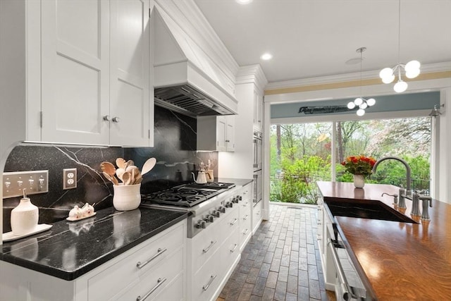 kitchen with custom range hood, brick floors, white cabinetry, ornamental molding, and a sink