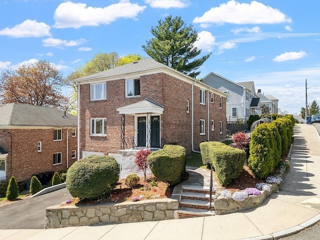 view of front of property with a residential view, aphalt driveway, and brick siding