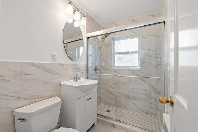 full bathroom featuring tile walls, a stall shower, vanity, a wainscoted wall, and toilet