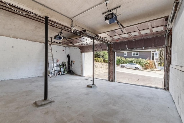 garage with a garage door opener and concrete block wall