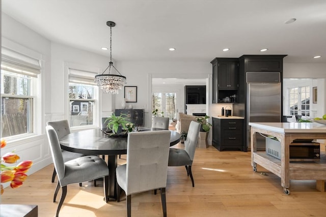 dining room featuring recessed lighting, light wood-type flooring, a chandelier, and a decorative wall