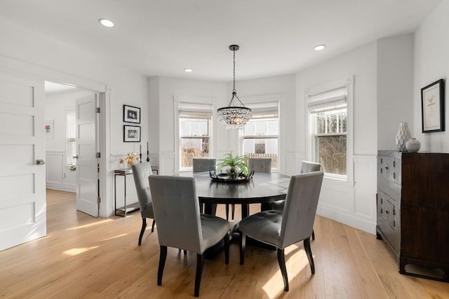 dining area featuring light wood-style flooring, recessed lighting, a wainscoted wall, and a chandelier