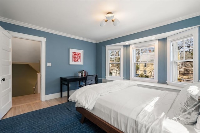 bedroom with multiple windows, wood finished floors, baseboards, and ornamental molding