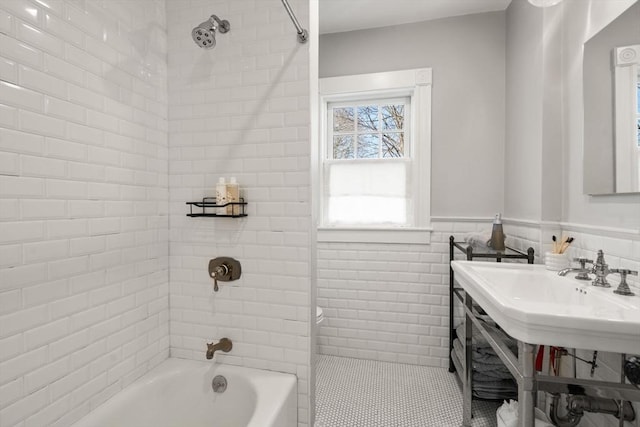 bathroom featuring a wainscoted wall, tile walls, and bathtub / shower combination