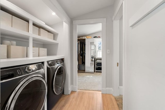 washroom featuring laundry area, baseboards, light wood-type flooring, and washer and clothes dryer