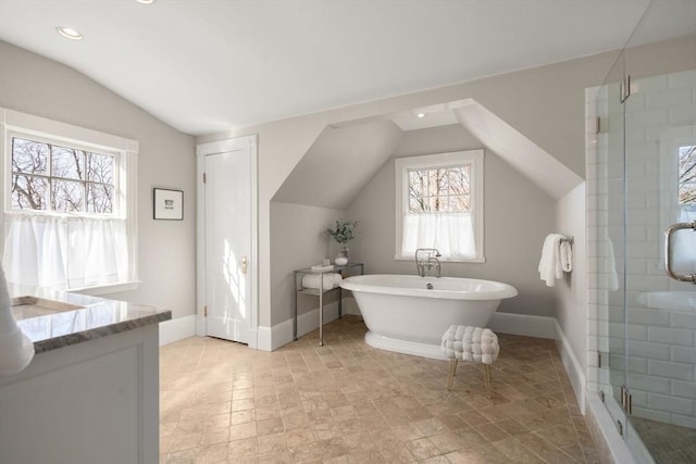 bathroom with baseboards, a freestanding bath, vaulted ceiling, a stall shower, and vanity