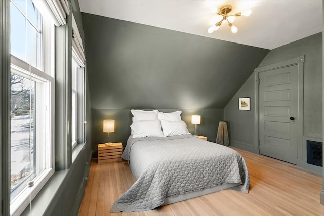 bedroom with multiple windows, lofted ceiling, and wood finished floors