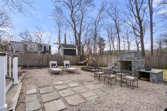 view of patio / terrace with a fenced backyard and an outdoor stone fireplace