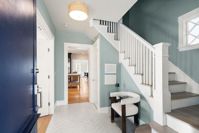 foyer entrance featuring stairway, parquet floors, and baseboards