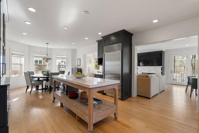 kitchen with plenty of natural light, light wood-style flooring, a fireplace, and built in fridge