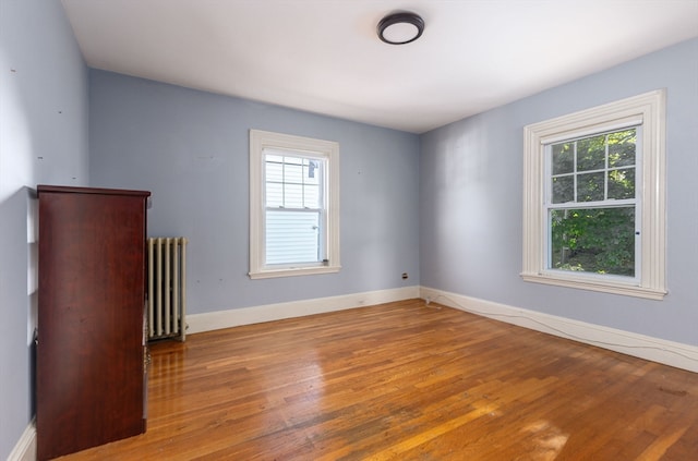 empty room featuring wood-type flooring and radiator heating unit