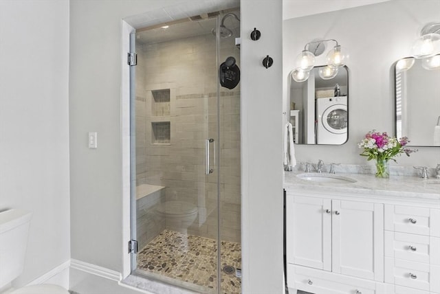 bathroom featuring washer / dryer, toilet, a shower stall, and double vanity