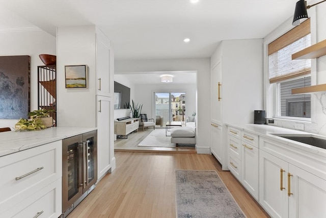 bar area featuring beverage cooler, light wood-style floors, recessed lighting, a sink, and stairs