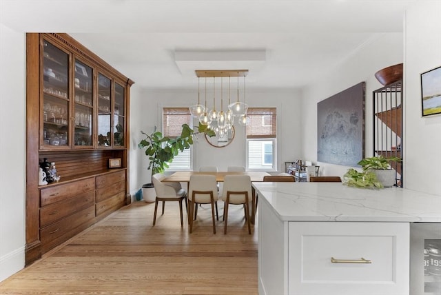dining space with wine cooler, light wood finished floors, and a chandelier