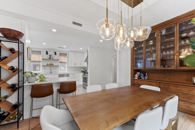 dining area with a chandelier, recessed lighting, light wood-type flooring, and crown molding