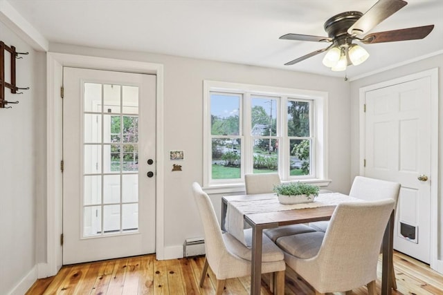 dining area featuring a ceiling fan, light wood-style floors, baseboards, and a baseboard radiator