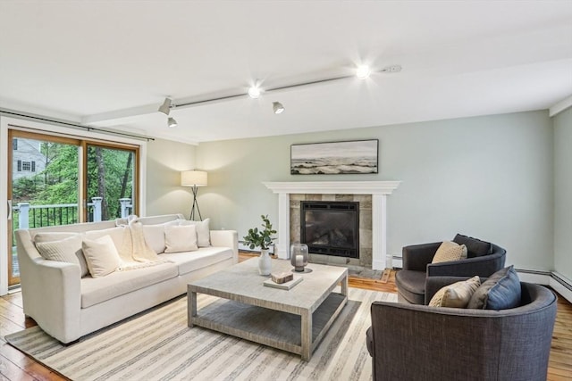 living room with a fireplace, a baseboard radiator, light wood-style flooring, and rail lighting