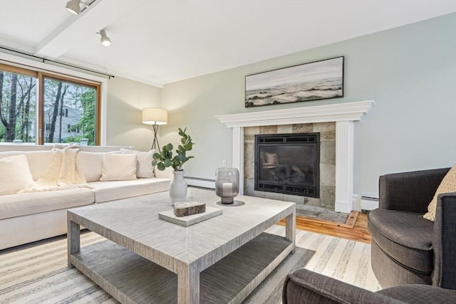 living room with light wood-style floors, track lighting, a tiled fireplace, and a baseboard heating unit