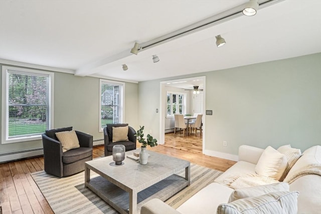 living area featuring light wood finished floors, a ceiling fan, baseboards, and baseboard heating