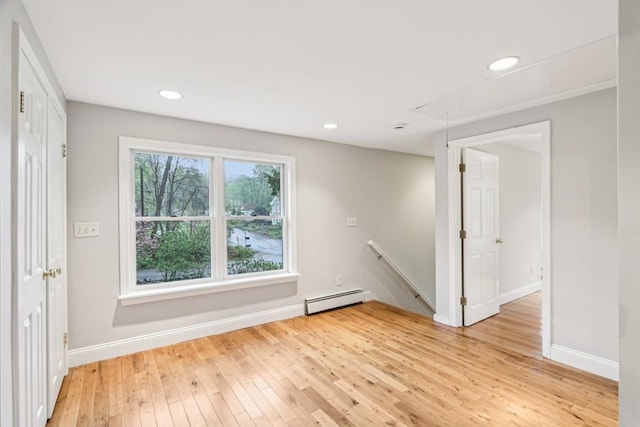 unfurnished room with baseboard heating, light wood-style flooring, recessed lighting, attic access, and baseboards