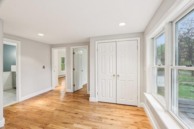 unfurnished bedroom featuring light wood finished floors, multiple windows, a closet, and recessed lighting