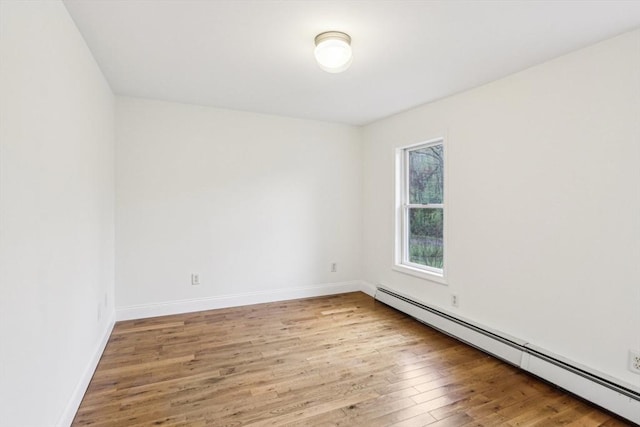 spare room with light wood-style floors, baseboards, and a baseboard heating unit