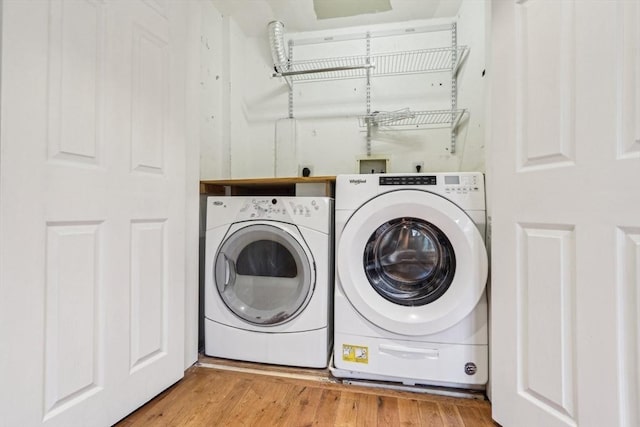 clothes washing area with washer and clothes dryer, laundry area, and wood finished floors