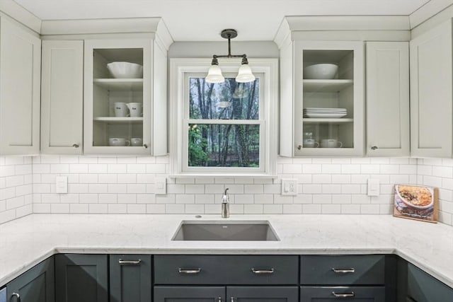 kitchen with a sink, decorative light fixtures, backsplash, and gray cabinets