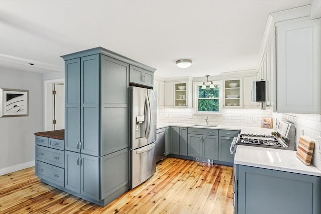kitchen featuring decorative backsplash, stainless steel fridge, light wood-style flooring, and a sink