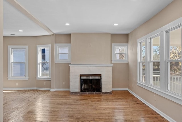 unfurnished living room with visible vents, a brick fireplace, baseboards, recessed lighting, and wood finished floors