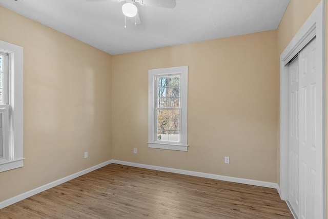 unfurnished bedroom with a closet, a ceiling fan, baseboards, and wood finished floors