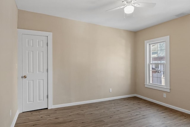 spare room featuring wood finished floors, baseboards, and ceiling fan