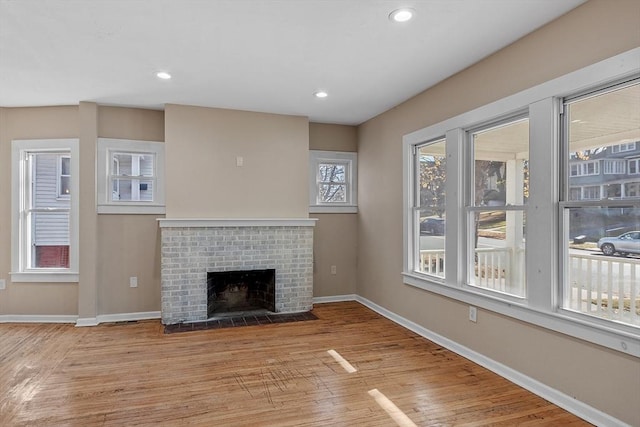 unfurnished living room featuring recessed lighting, a fireplace, baseboards, and wood finished floors