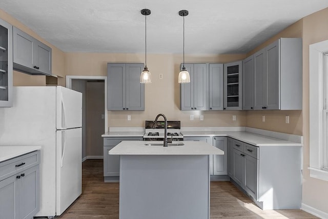 kitchen with gray cabinets, wood finished floors, freestanding refrigerator, and a sink