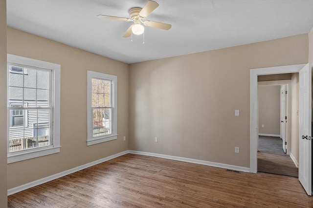 spare room featuring visible vents, a ceiling fan, baseboards, and wood finished floors