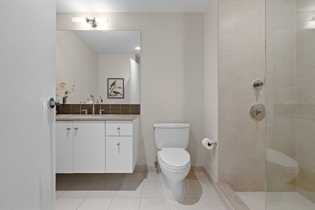 bathroom featuring toilet, tile patterned floors, vanity, and a tile shower