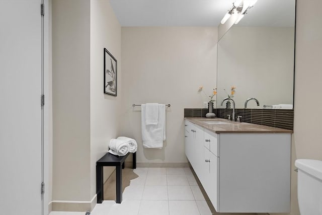 bathroom featuring toilet, decorative backsplash, vanity, baseboards, and tile patterned floors