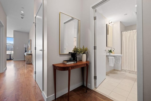 corridor with light wood finished floors and baseboards