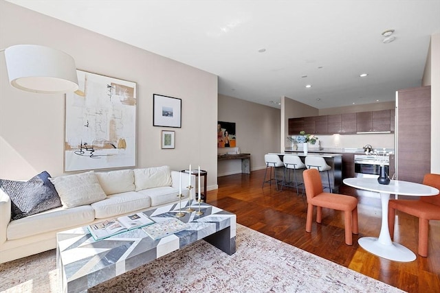 living area with dark wood-style flooring, baseboards, and recessed lighting