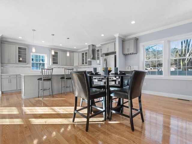 dining space featuring light hardwood / wood-style floors and crown molding